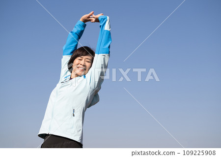 Healthy woman stretching and warming up outside 109225908