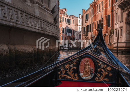 A serene gondola glides along a picturesque canal in Venice, Italy, showcasing the iconic boat and classic Venetian architecture. The image evokes the timeless charm and romance of the city. A serene gondola glides along a picturesque canal in Venice, Italy, showcasing the iconic boat and classic Venetian architecture. The image evokes the timeless charm and romance of the city. 109225974