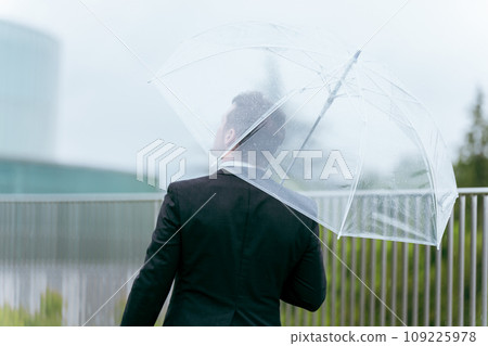 Foreign businessman holding an umbrella on a rainy day (rainy season, typhoon, abnormal weather, weather) 109225978