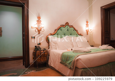 Luxurious white, green, and gold themed bedroom at Palazzo Santa Maria in Venice, Italy. Rectangular beds with no bedside tables or seating. Unknown flooring and angle. Luxurious white, green, and gold themed bedroom at Palazzo Santa Maria in Venice, Italy. Rectangular beds with no bedside tables or seating. Unknown flooring and angle. 109225979