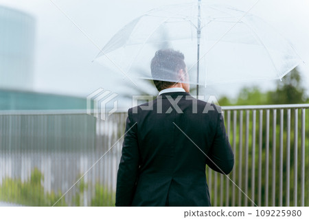 Foreign businessman holding an umbrella on a rainy day (rainy season, typhoon, abnormal weather, weather) Foreign businessman holding an umbrella on a rainy day (rainy season, typhoon, abnormal weather, weather) 109225980