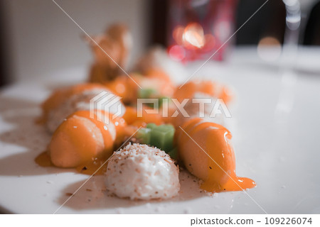 A white plate filled with a variety of appetizers and desserts, accompanied by a glass of wine, set on a simple dining table. A white plate filled with a variety of appetizers and desserts, accompanied by a glass of wine, set on a simple dining table. 109226074