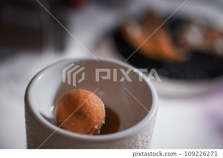 A side angle view of a white cup with a donut inside on a white tabletop, creating a sense of anticipation and excitement for the upcoming meal. 109226271