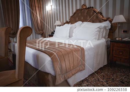 Luxurious hotel room with large bed and soft lighting, creating a relaxing atmosphere. Striped walls add a stylish touch. Part of a collection of Venice photos. Luxurious hotel room with large bed and soft lighting, creating a relaxing atmosphere. Striped walls add a stylish touch. Part of a collection of Venice photos. 109226338