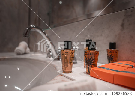 A white sink in a bathroom with shampoo, body wash, and an orange box. Part of a collection of Venice photos, including interior shots of luxury establishments. 109226588