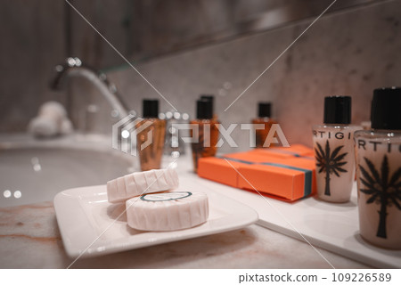 Modern bathroom with white marble sink and orange soaps. Clean, minimalist design with no decorative items. Perfect for a sleek, contemporary home. Modern bathroom with white marble sink and orange soaps. Clean, minimalist design with no decorative items. Perfect for a sleek, contemporary home. 109226589