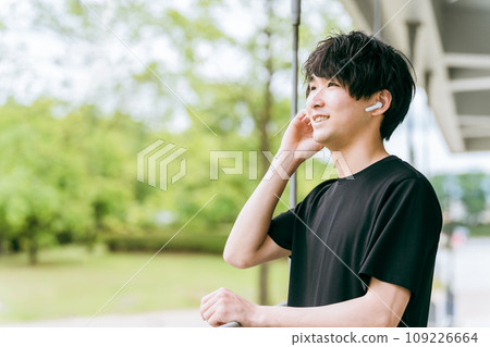 Man listening to music with wireless earphones and using hands-free earphones during sports/training 109226664