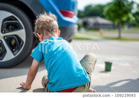Children sitting on a driveway behind a vehicle in a blind spot out of view of the driver.  109229093