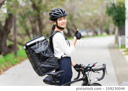 一名女送餐員,前面騎著公路車,背著送貨包,豎起大拇指 一名女送餐員,前面騎著公路車,背著送貨包,豎起大拇指 109230046