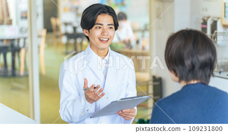 一個穿白大褂的年輕人，醫生，顧問，與女人交談 109231800