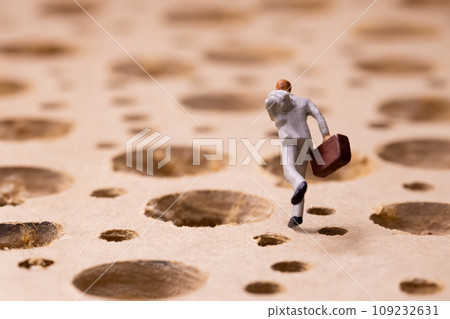 Businessman running through a place full of holes 109232631