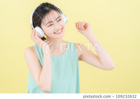 黃色背景中戴著耳機聽音樂的年輕女性 109232632