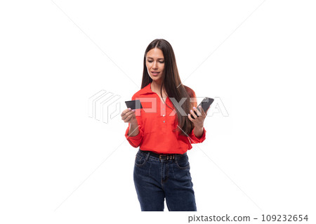 young caucasian brunette employee woman dressed in red blouse uses plastic card and smart phone 109232654