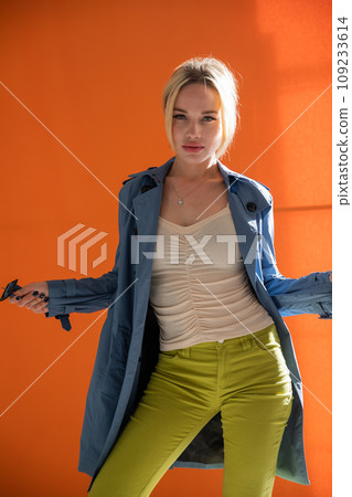Fashionable blonde woman in autumn raincoat on orange background 109233614