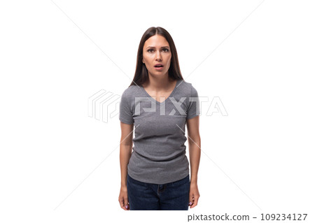 young surprised brunette promoter woman dressed in a gray t-shirt on a white background young surprised brunette promoter woman dressed in a gray t-shirt on a white background 109234127