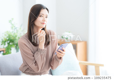 年輕女子在客廳的沙發上使用智慧型手機 109235475