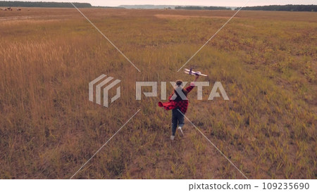 Happy schoolgirl runs across boundless field clutching toy airplane in hand Happy schoolgirl runs across boundless field clutching toy airplane in hand 109235690