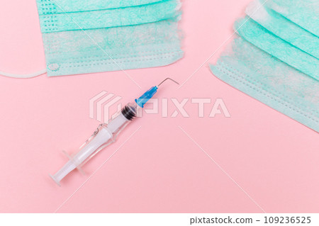 Broken Medical Syringe and Torn Medical Face Mask on the Pink Background 109236525