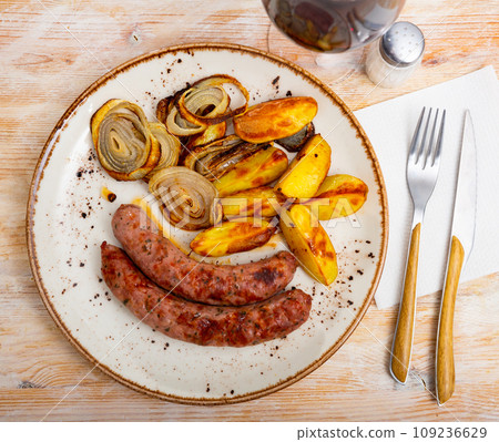 Grilled meat sausages served with potatoes fried with onion Grilled meat sausages served with potatoes fried with onion 109236629
