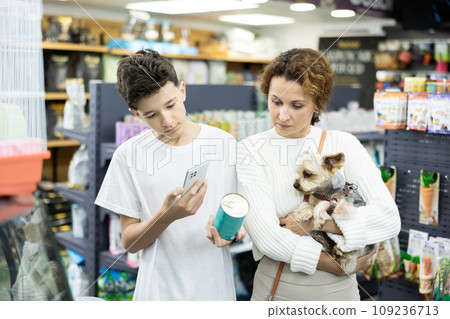 Family with Yorkshire terrier puppy is scaning QR code on dog food tin can at pet shop Family with Yorkshire terrier puppy is scaning QR code on dog food tin can at pet shop 109236713