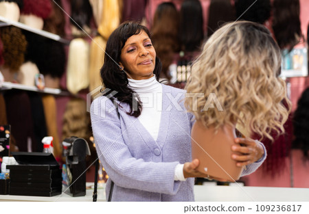 Woman choosing natural wig at specialty boutique 109236817