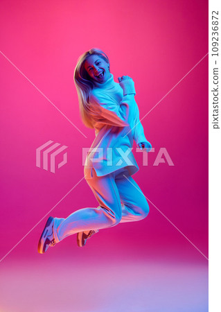 Full length portrait of young girl, happy young woman jumping expressing joy because winter sale season begun against gradient pink background. 109236872