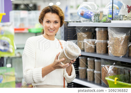 Young woman in animal goods store examines packaging of dry food for turtles 109236882