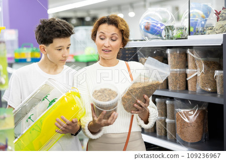 Woman with teenage son selecting food for turtles in pet store Woman with teenage son selecting food for turtles in pet store 109236967