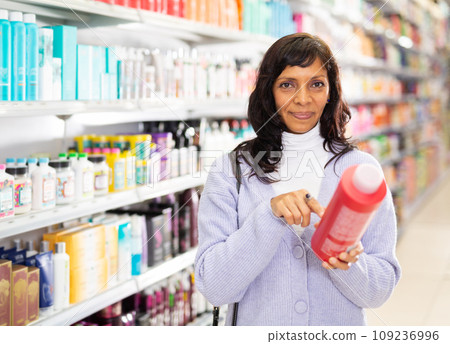 Adult Latina choosing haircare cosmetics in specialized boutique 109236996