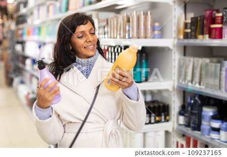 Woman choosing hair shampoo in cosmetics store 109237165
