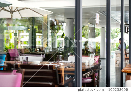 Hotel restaurant space with tables set for dinner at luxury resort, view through by window. 109238696