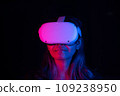Young asian woman using at home Virtual Reality headset playing VR video games, neon pink blue light 109238950