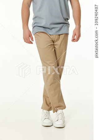 guy with crossed legs. man wearing white sneakers and casual beige pants on studio background guy with crossed legs. man wearing white sneakers and casual beige pants on studio background 109240487