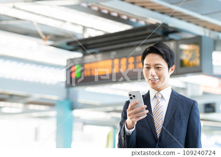 一位商人在車站看著智慧型手機。照片由京王電鐵株式會社提供。 一位商人在車站看著智慧型手機。照片由京王電鐵株式會社提供。 109240724