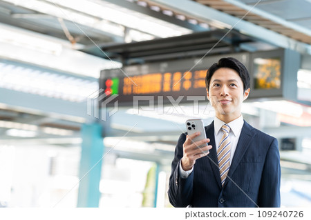 A businessman looking at his smartphone at the station. Photo provided by Keio Electric Railway Co., Ltd. 109240726