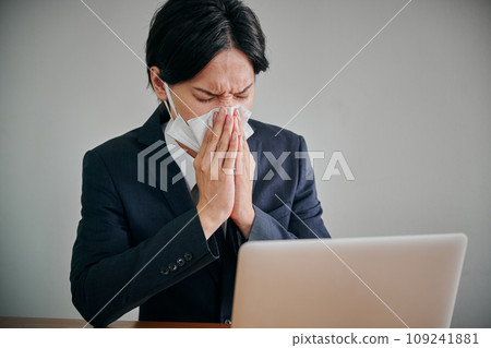 Young male office worker wiping his runny nose with a tissue Young male office worker wiping his runny nose with a tissue 109241881