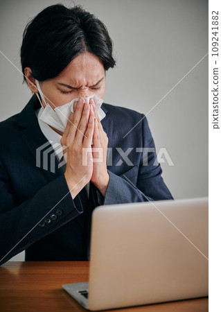Young male office worker wiping his runny nose with a tissue Young male office worker wiping his runny nose with a tissue 109241882