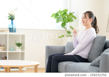 一個女人坐在沙發上，喝著咖啡 109242356