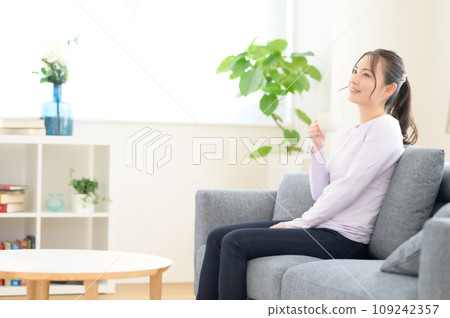 一個女人坐在沙發上，喝著咖啡 109242357