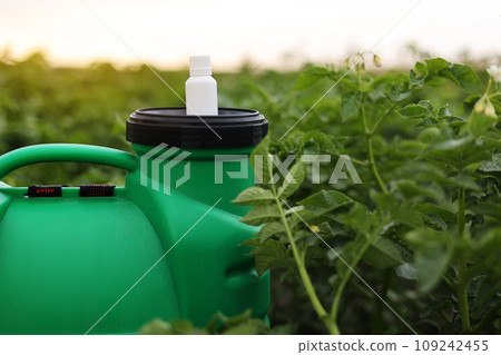 White little bottle of pesticide, herbicide for protecting plants from diseases and pests with mock up stands on container sprayer on natural green garden background. Agricultural seasonal work White little bottle of pesticide, herbicide for protecting plants from diseases and pests with mock up stands on container sprayer on natural green garden background. Agricultural seasonal work 109242455