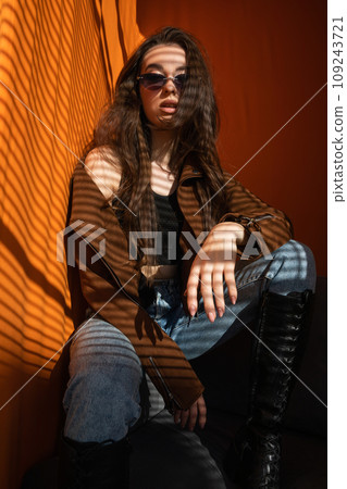 Beautiful fashionable young woman on orange sun background Beautiful fashionable young woman on orange sun background 109243721