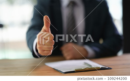Businessman showing thumb up at work in office closeup 109244200
