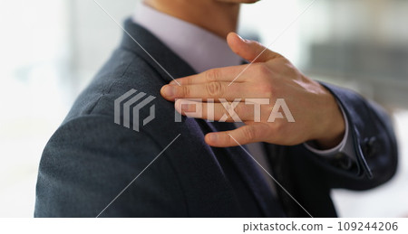 Businessman in business suit brushing off dust or dandruff from his shoulder closeup Businessman in business suit brushing off dust or dandruff from his shoulder closeup 109244206