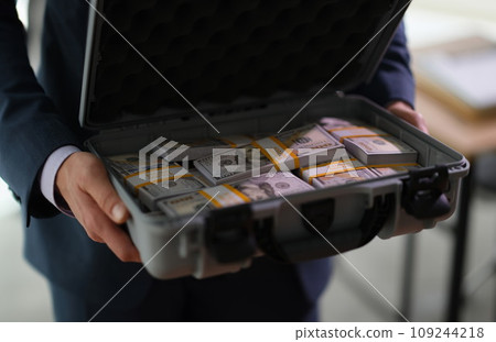 Banker holding suitcase with many dollar bills closeup 109244218