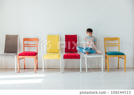 boy and many different chairs in the interior of a white room 109244513
