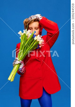 Portrait of weird girl in unusual, strange, variegated colored outfit and posing with flower bunch against color studio background. Portrait of weird girl in unusual, strange, variegated colored outfit and posing with flower bunch against color studio background. 109244559