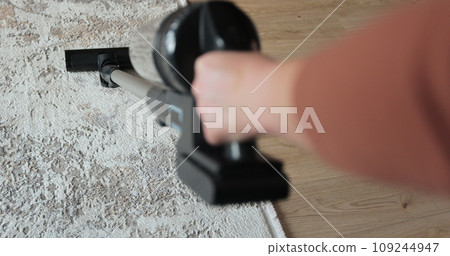 Young woman cleaning carpet with cordless vacuum cleaner in modern living room. House cleaning concept. 109244947