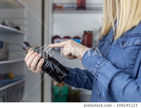 Woman reads instructions for food products at home. Checking labels on goods. Study of product compositions. Search Internet for descriptions of product gradients. Useful or harmful. Nutritionology 109245123