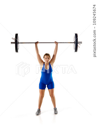 Full-length image of professional athlete, young woman training, lifting heavy weight, barbell against white background Full-length image of professional athlete, young woman training, lifting heavy weight, barbell against white background 109245674