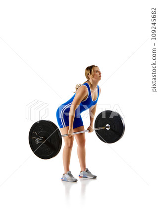 Young woman in sportswear training, lifting heavy barbell against white background Young woman in sportswear training, lifting heavy barbell against white background 109245682